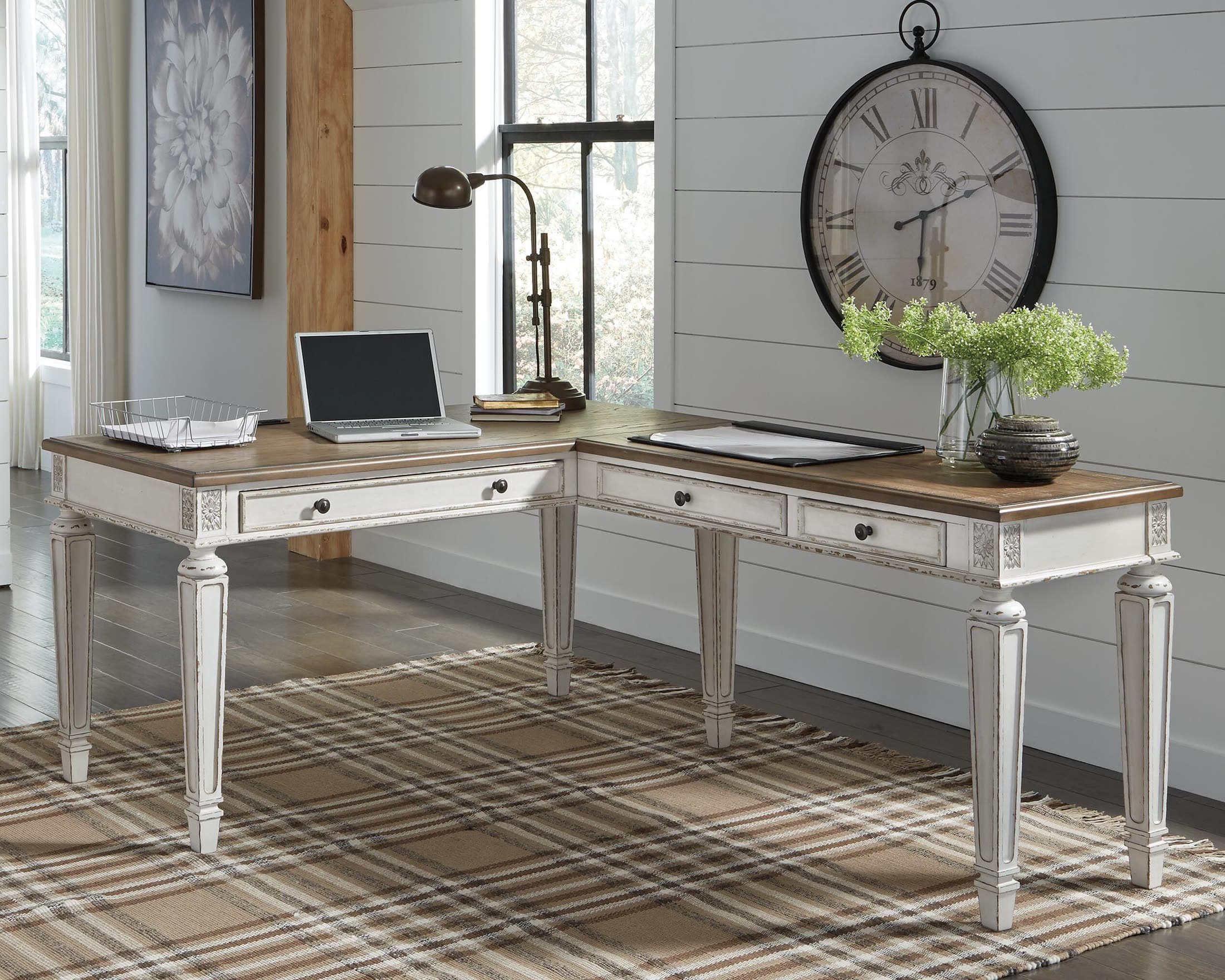 White L-shaped home office desk with a laptop, lamp and drawers