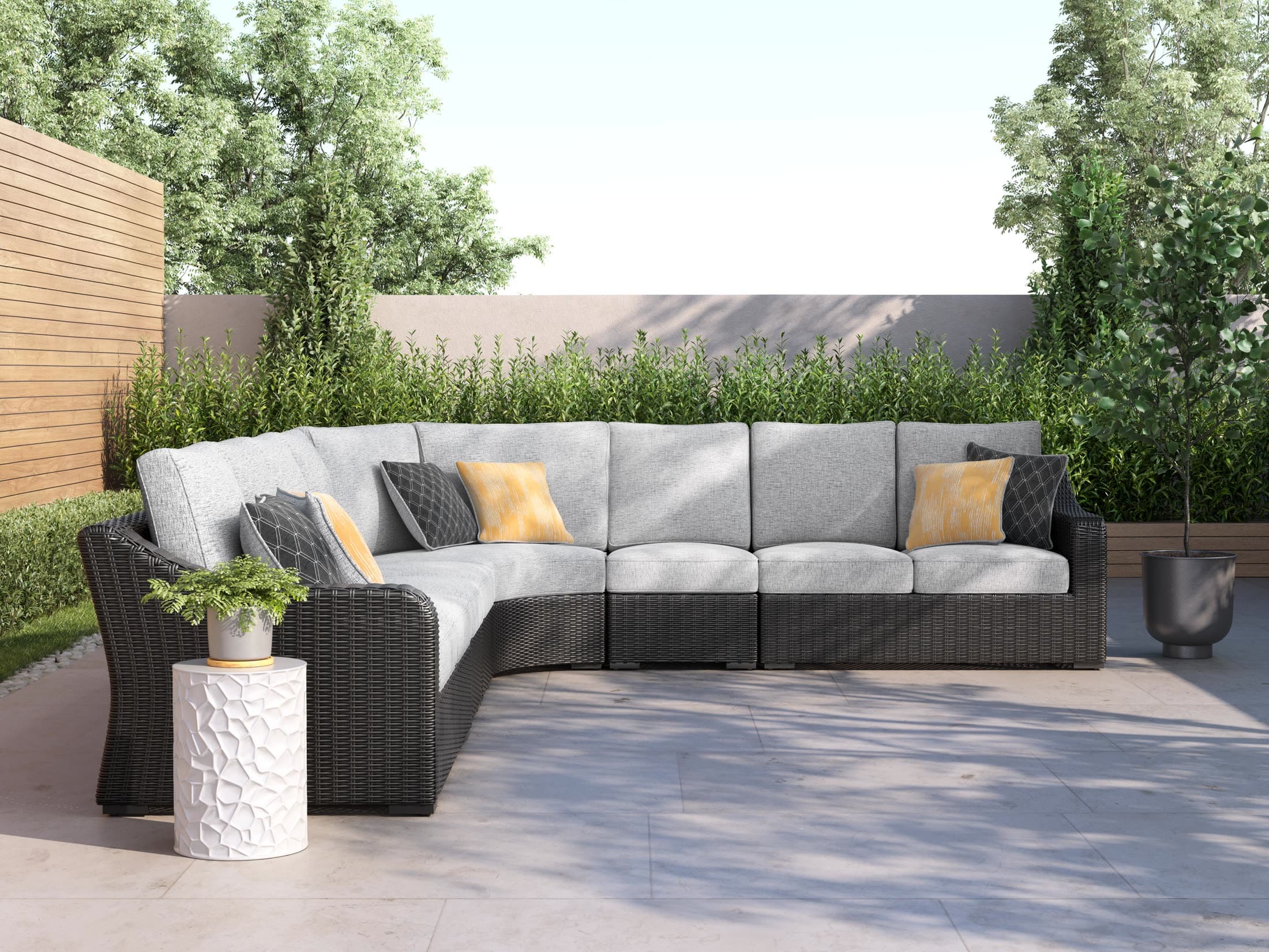 Wicker outdoor sectional with cushions on a patio beside planters